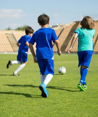 pexels photo 8941577 8941577 Three kids play soccer on a bright outdoor field, enjoying teamwork and sports.