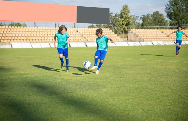 pexels photo 8941621 8941621 Children playing football on a sunny day in a Portuguese stadium.